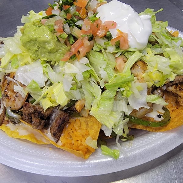 Loaded nachos with grilled chicken, steak, shrimp, lettuce, guacamole, pico de gallo, and sour cream.