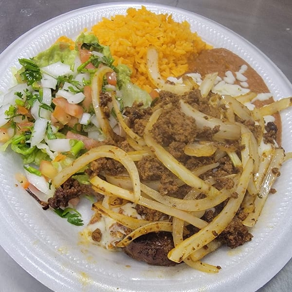 Mexican dish with steak, onions, rice, refried beans, guacamole, and pico de gallo.